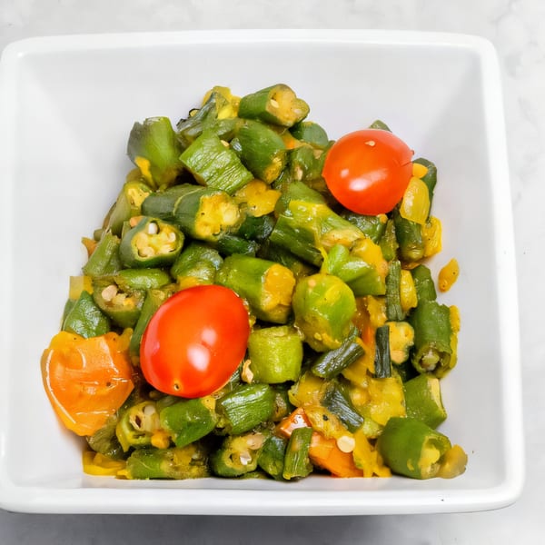 Indian Bhindi Masala, a dish of cooked okra, tomatoes, and peppers in a white bowl.